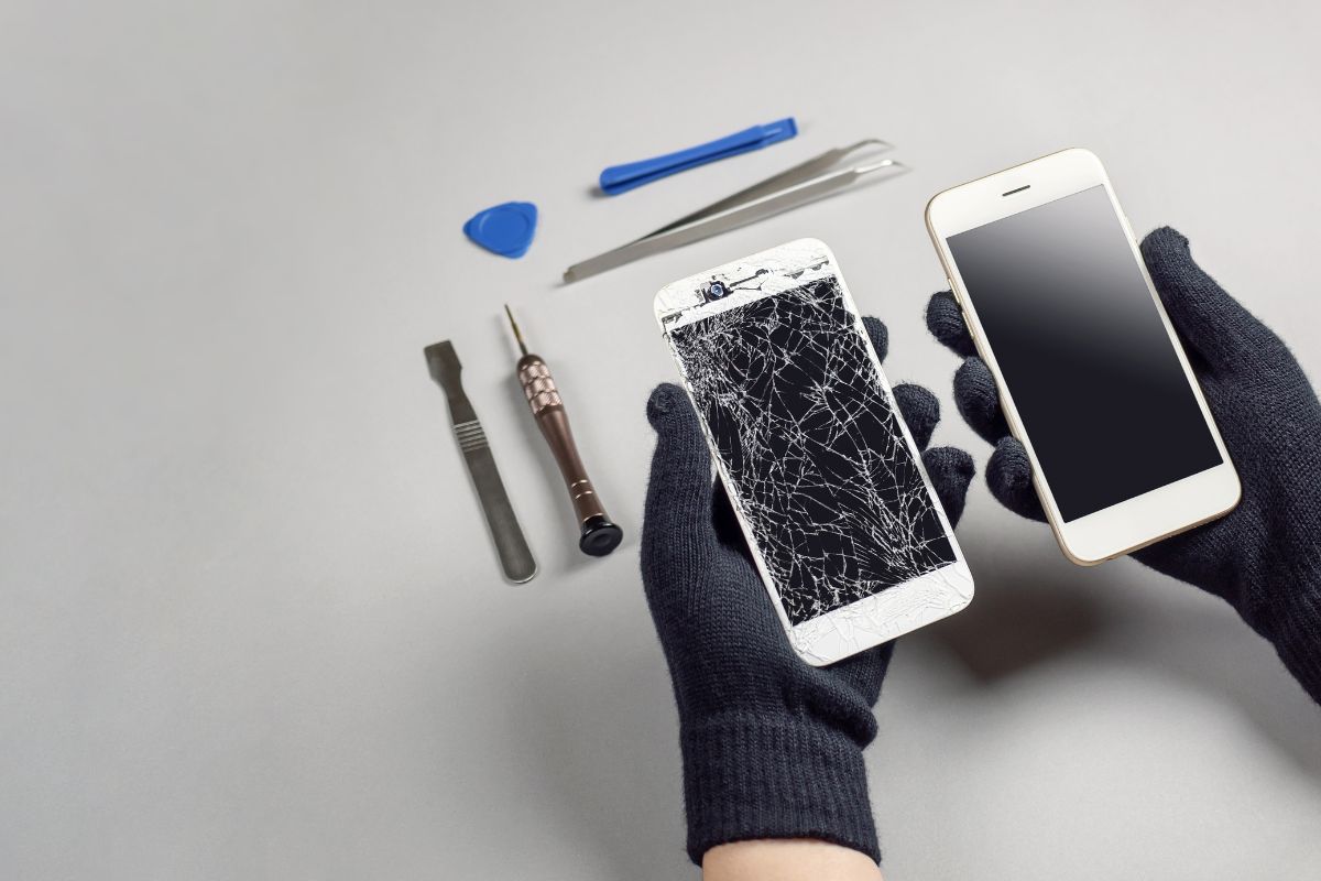 Deux smartphones, l'un avec écran cassé et l'autre intact, tenus par des mains gantées avec des outils de réparation à côté.
